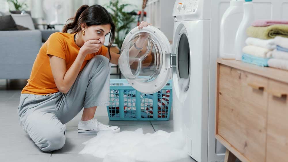 Broken washing machine overflowing with soap suds
