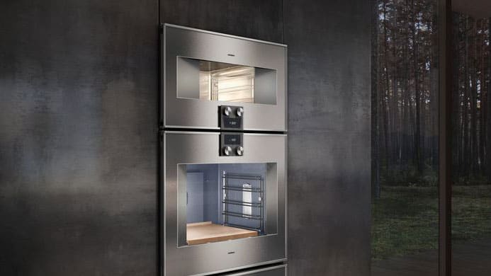 Gaggenau steam oven stacked above matching wall oven, both flush-mounted in minimalist cabinetry