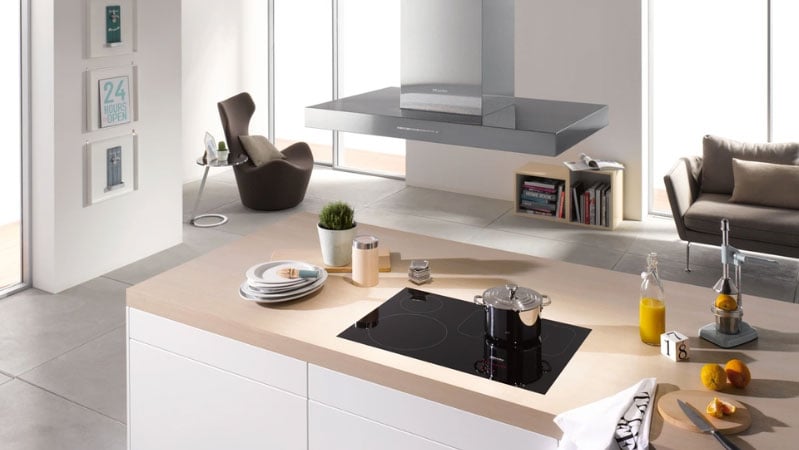 Kitchen island featuring an induction cooktop beneath a suspended island hood, sized and hung at the ideal height